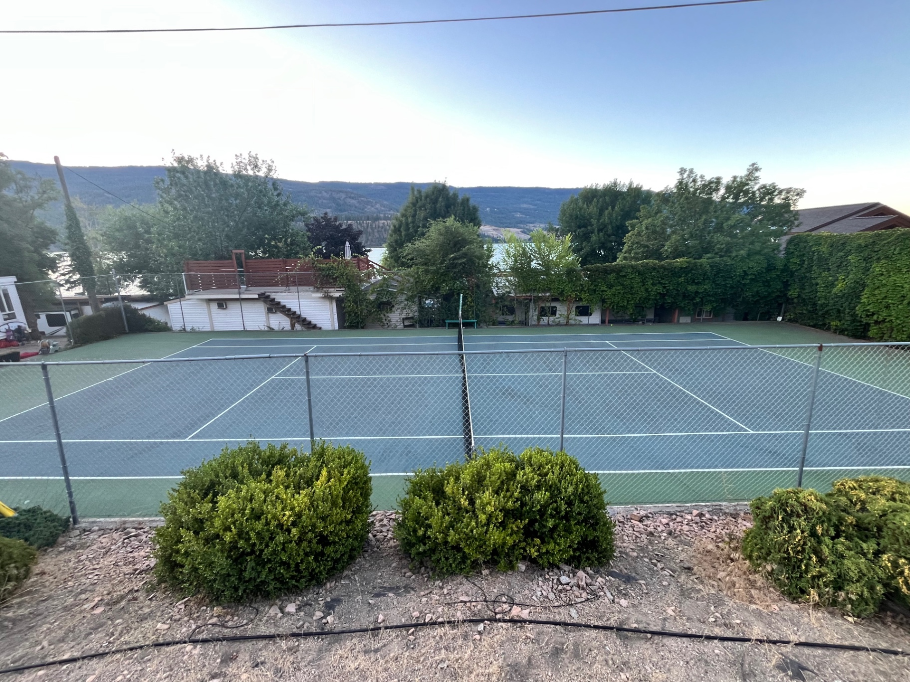 Tennis court with Kalamalka Lake and hills in the background